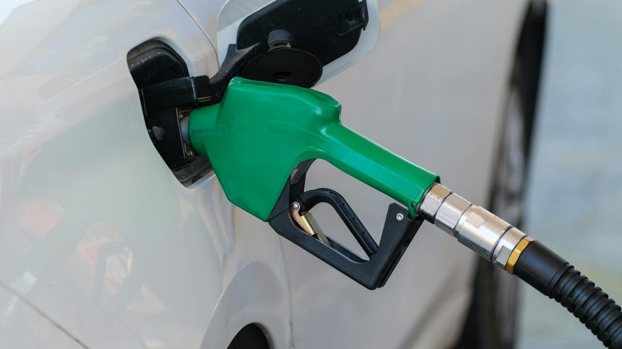 gas pump nozzle filling the white car