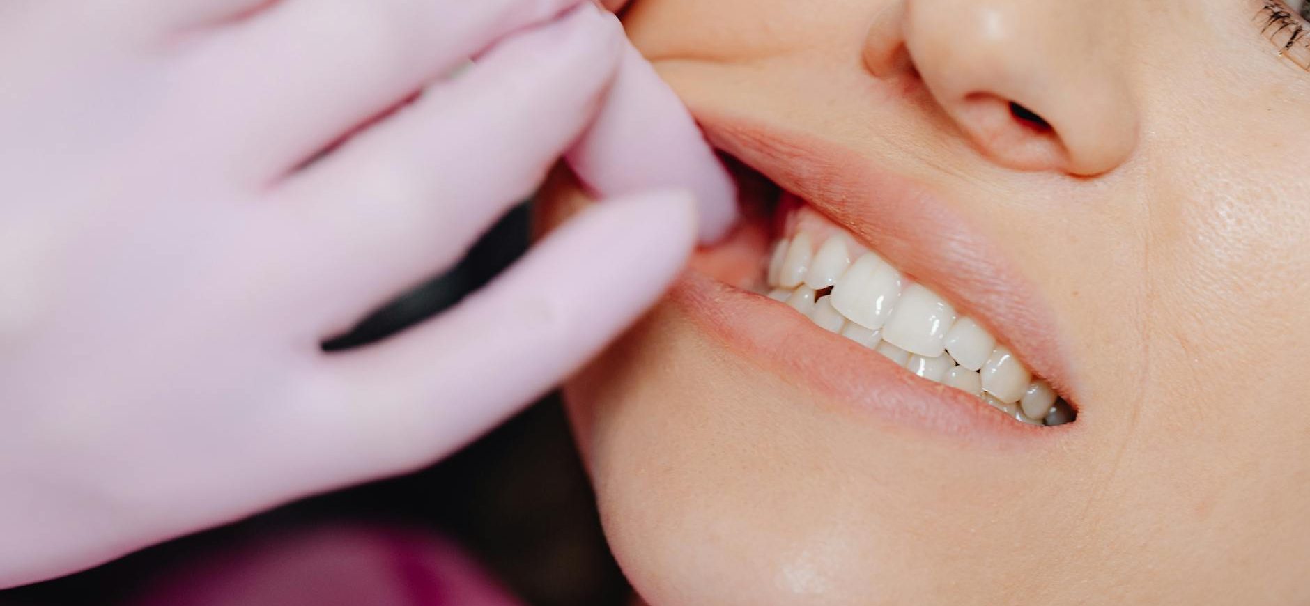 a person wearing latex gloves checking a woman s teeth