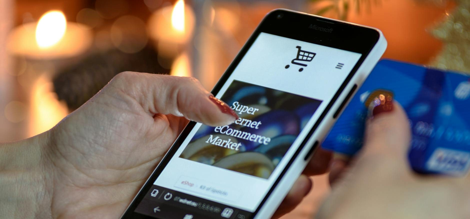 person using black and white smartphone and holding blue card