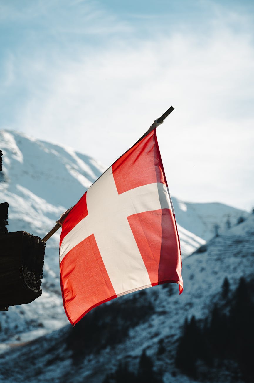 swiss flag over snowy french alps scenic view