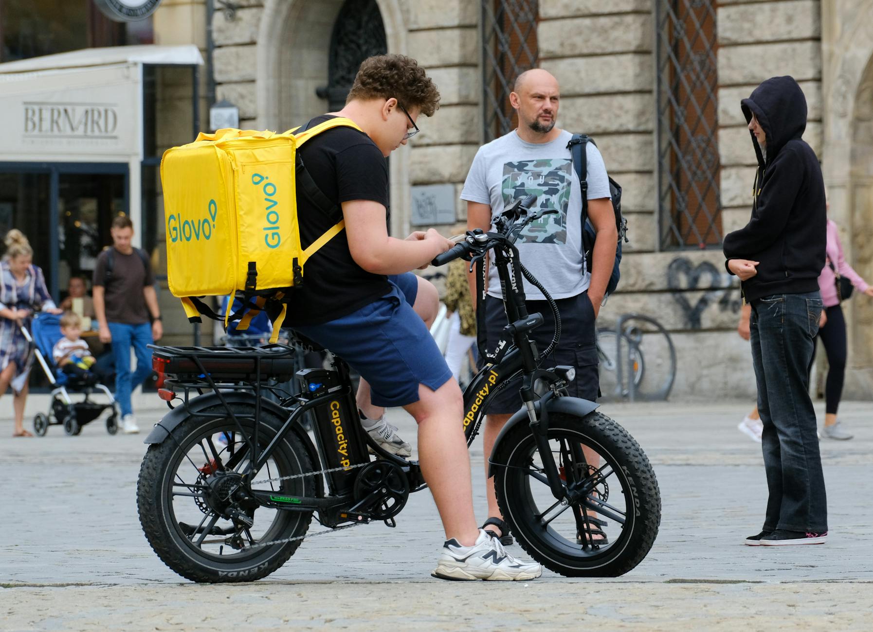 courier with glovo bag on electric bicycle in city